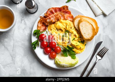 Colazione con uova strapazzate, pancetta e verdure fritte, vista dall'alto, spazio fotocopie. Foto Stock
