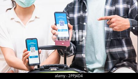 coppia donna e uomo pronto viaggio mostrando e puntando il certificato di passaporto sanitario vaccino digitale Foto Stock
