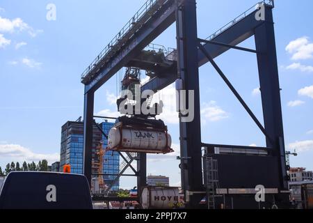 Kiel, Germania - 27.dicembre 2022: Una grande gru industriale solleva container pesanti con carico nel porto di Kiel in condizioni di sole. Foto Stock