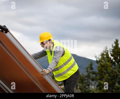 L'uomo lavora su un sistema di energia rinnovabile con pannello solare per acqua calda Foto Stock