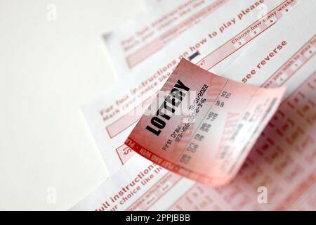 Il biglietto della lotteria rossa si trova su fogli da gioco rosa con i numeri da contrassegnare per giocare alla lotteria. Concetto di gioco alla lotteria o dipendenza dal gioco d'azzardo. Primo piano Foto Stock