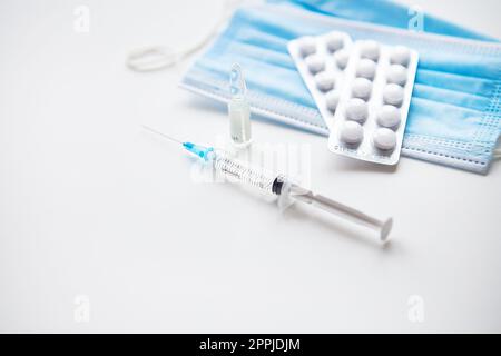 Preparazione per la vaccinazione contro il covid-19. Siringa, vaccino, pillole, maschera medica. Foto Stock