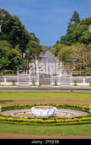 Scannerizzata una fotografia storica a colori che mostra la vista dal Palazzo dell'Indipendenza a Saigon attraverso il cancello d'ingresso su una strada trafficata Foto Stock