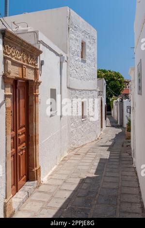 Uno stretto vicolo con case bianche di paglia nel villaggio di Lindos sull'isola greca di Rodi nel Mar Egeo Foto Stock