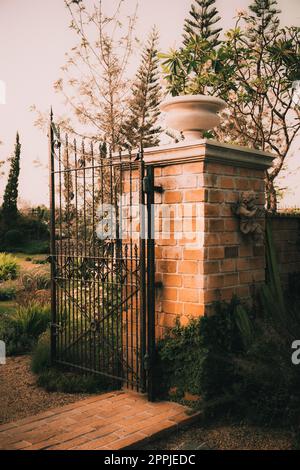 Vecchio giardino in ghisa cancello in acciaio su arco colonna di pietra parete di ingresso Foto Stock