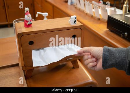 Donne che prelevano la carta di tessuto a mano dalla scatola di tessuto Foto Stock