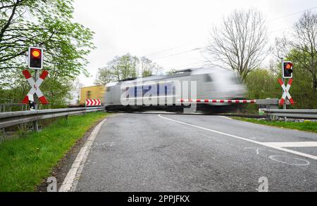 24 aprile 2023, bassa Sassonia, Neustadt am Rübenberge: Un treno passa il passaggio di livello dove un'auto è stata colpita da un treno la domenica mattina. Dopo l'incidente mortale nella regione di Hannover, la polizia sta facendo tutto il possibile per chiarire la causa. Nell'incidente, tre giovani erano morti all'inizio della domenica mattina (23.04.2023) quando la loro auto è stata colpita da un treno regionale sul passaggio di livello. Secondo la polizia, avevano guidato fino all'attraversamento del livello, nonostante le mezze barriere fossero state chiuse. Foto: Julian Stratenschulte/dpa Foto Stock