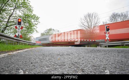 24 aprile 2023, bassa Sassonia, Neustadt am Rübenberge: Un treno passa il passaggio di livello dove un'auto è stata colpita da un treno la domenica mattina. Dopo l'incidente mortale nella regione di Hannover, la polizia sta facendo tutto il possibile per chiarire la causa. Nell'incidente, tre giovani erano morti all'inizio della domenica mattina (23.04.2023) quando la loro auto è stata colpita da un treno regionale sul passaggio di livello. Secondo la polizia, avevano guidato fino all'attraversamento del livello, nonostante le mezze barriere fossero state chiuse. Foto: Julian Stratenschulte/dpa Foto Stock