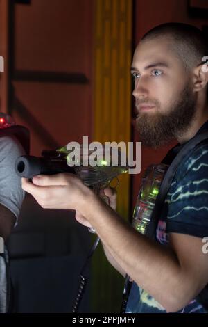 lettore laser tag con barba che tiene la pistola giocattolo nel labirinto del gioco Foto Stock