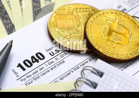 La penna, le bitcoins e le fatture del dollaro è situata sul modulo di imposta 1040 US Reddito Individuale dichiarazione. Il tempo di pagare le tasse Foto Stock