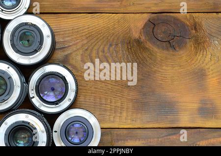 Diverse lenti fotografiche giacciono su uno sfondo di legno marrone. Spazio per il testo Foto Stock