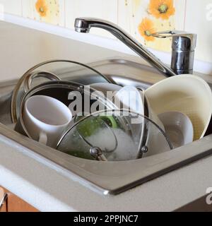 I piatti sporchi e gli elettrodomestici da cucina non lavati riempivano il lavandino della cucina Foto Stock