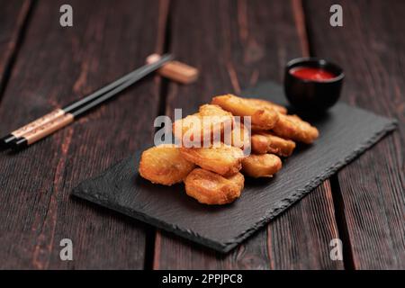 Pezzi di pollo fritti su tavola di pietra con bastoncini - cibo asiatico Foto Stock