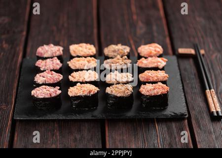 Set di Gunkan Maki Sushi con diversi tipi di salmone di pesce, capesante, persico, anguilla, gamberi e caviale su fondo di legno. Menu sushi. Sushi giapponese, set di gunkan Foto Stock