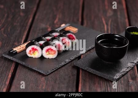 Maki sushi roll con avocado di salmone e caviale di tobiko servito a bordo nero primo piano - cibo giapponese Foto Stock