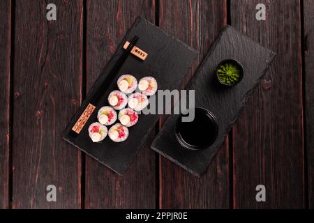Maki sushi roll con avocado di salmone e caviale di tobiko servito sulla tavola nera vista dall'alto - cibo giapponese Foto Stock