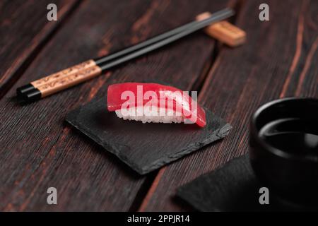 Delizioso sushi maguro tonno. Nigiri con tonno su fondo nero e legno. Cucina giapponese tradizionale Foto Stock