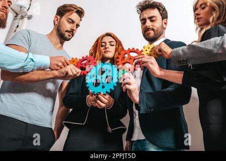 Lavoro di squadra di imprenditori lavorano insieme e combinano le parti di ingranaggi come partnership e integrazione Foto Stock