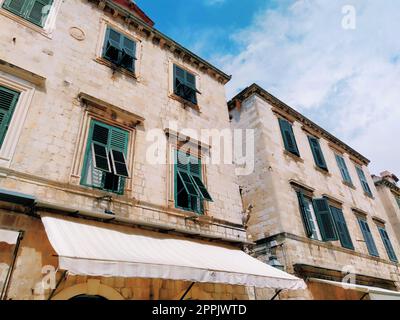 Stradun, Stradone è la strada principale del centro storico di Dubrovnik in Croazia. Attrazioni architettoniche. La facciata dell'edificio con persiane di metallo verde sulle finestre. 14 agosto 2022 Foto Stock