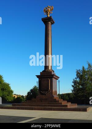 Petrozavodsk, Carelia, 3 agosto 2022 Monumento-stele città di gloria militare, titolo onorario. Colonna in granito con aquila a due teste in bronzo. Piedistallo sul vicolo delle città gemelle, Piazza Kirov Foto Stock