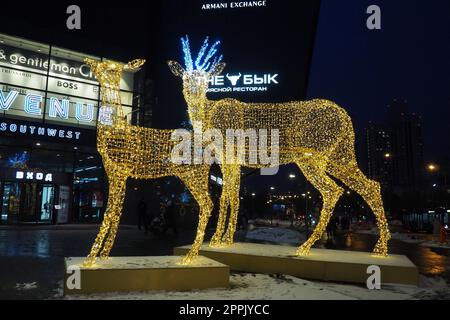 Mosca, Russia, 17 gennaio 2023 Metro Yugo-Zapadnaya. Decorazioni natalizie di fronte al centro commerciale. Decorazioni stradali di Capodanno sotto forma di cervo frizzante. Figura di cervo fatta di ghirlande d'oro giallo. Foto Stock