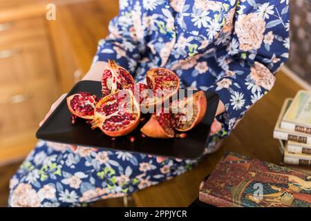 La donna ha un granato rosso maturo. Frutti di melograno rosso maturo sulla soglia dei finestrini. Vegetariano, vitamine biologiche, disintossicazione, concetto di dieta. Frutta granata biologica e benefica. Primo piano. Foto Stock