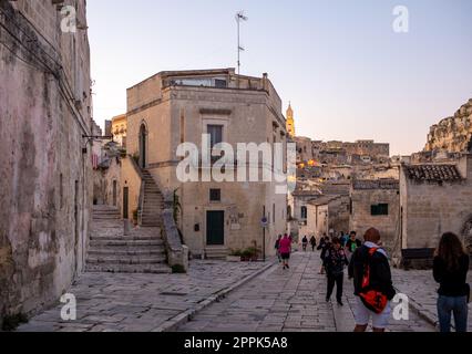 Il turista durante una passeggiata su strada acciottolata nei Sassi di Matera, quartiere storico della città di Matera. Foto Stock