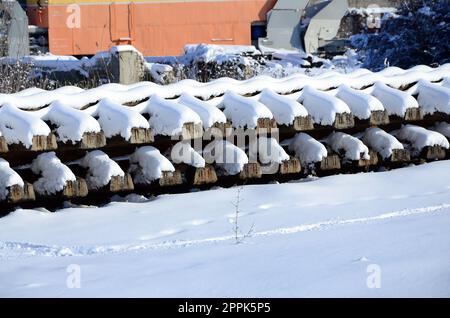 Molti vecchi binari e traversine sono impilati in un magazzino ferroviario in inverno. Il concetto di rinnovamento di una ferrovia logora Foto Stock
