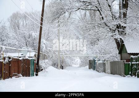 Un paesaggio invernale rustico con alcune vecchie case e un'ampia strada coperta da uno spesso strato di neve Foto Stock