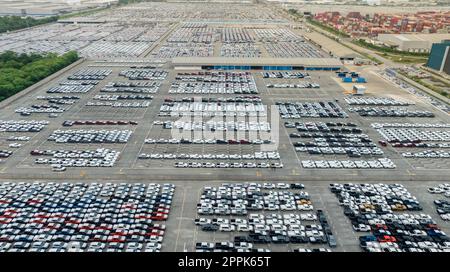 Vista aerea del parco auto nuovo presso il parcheggio della fabbrica. Sopra la vista c'erano molte auto parcheggiate di fila. Industria automobilistica. Logistica e catena di fornitura. Importa o esporta auto nuove nel magazzino vicino al porto. Foto Stock