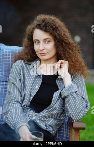 Ritratto all'aperto di una giovane donna dai capelli ricci Foto Stock