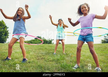 Montato in una frenesia di hula. un gruppo di giovani ragazze che giocano con i cerchi di lula nel parco. Foto Stock