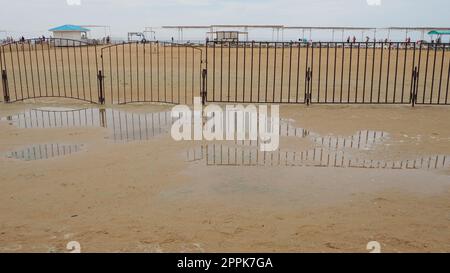 Vityazevo Russia, 10 agosto 2021 Una pozzanghera su una spiaggia di quarzo sabbiosa dopo una pioggia intensa. Conseguenze del maltempo e del tifone. Il limite della stagione delle vacanze in spiaggia. Turisti sullo sfondo Foto Stock