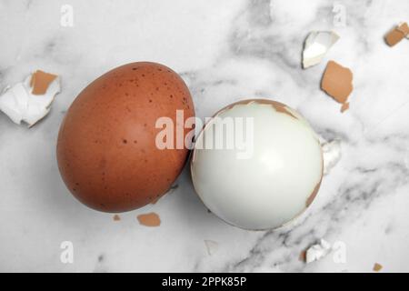 Uova bollite e pezzi di guscio su tavola di marmo bianco, giacitura piatta Foto Stock