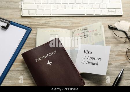 Moldova, Ceadir-lunga - 13 giugno 2022: Passaporti con francobolli, penna, occhiali e tastiera per computer su tavolo di legno Foto Stock