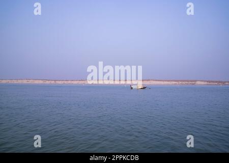 Vista panoramica del fiume Padma su una barca da pesca con un'isola di sabbia sotto il cielo blu Foto Stock