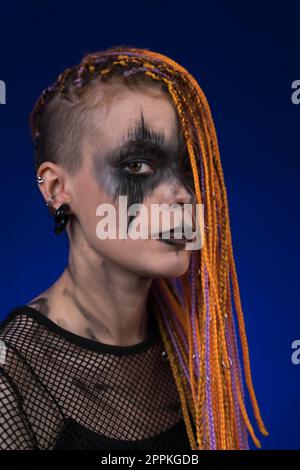 Drammatico ritratto di giovane donna con creativo horror nero scena trucco dipinto sul viso e colore arancione senza pericolosi capelli Dreadlocks Foto Stock