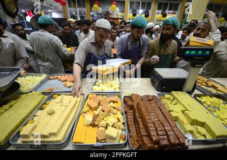 La gente acquista dolci tradizionali in preparazione alle prossime celebrazioni di Eid al-Fitr in un negozio di Peshawar, Pakistan, il 20 aprile 2023. EID al-Fitr segna la fine del mese santo islamico del Ramadan. (Foto di Hussain Ali/Pacific Press/Sipa USA) Foto Stock