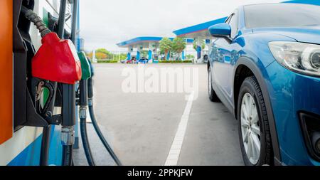 Rifornimento di SUV blu di lusso presso la stazione di servizio. Rabboccare con benzina. Pistola erogatrice di carburante per il rifornimento della pompa di benzina nella stazione di servizio. Industria della benzina. Concetto di prezzo della benzina e crisi petrolifera. Crisi energetica. Foto Stock