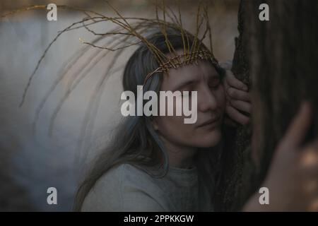 Primo piano antica donna in stile celtico che abbraccia l'albero e prega ritratto immagine Foto Stock