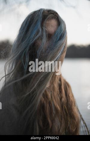 Primo piano lungo grigio marrone capelli nascondere il viso donna con vento ritratto immagine Foto Stock