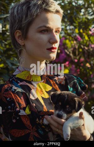 Primo piano donna a capelli corti con cucciolo in orchard ritratto Foto Stock