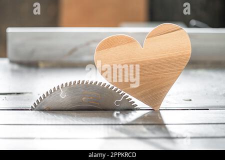 un cuore di legno su una circolare nella falegnameria. Amo il legno Foto Stock