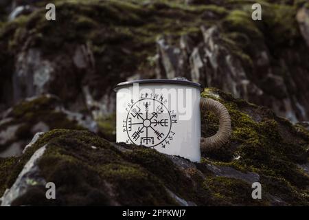 Primo piano tazza di smalto con rune sulla foto del concetto di roccia Foto Stock