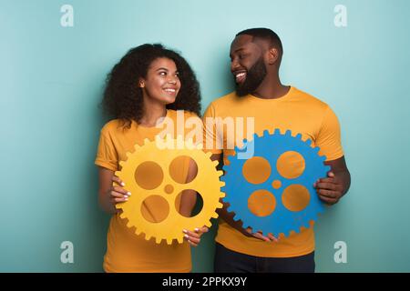 Coppia con ingranaggi in mano su fondo azzurro. Concetto di integrazione europea e il partenariato Foto Stock