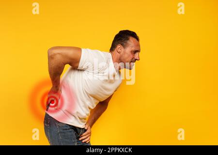 Dolorante di uomo con il mal di schiena. Sfondo giallo Foto Stock