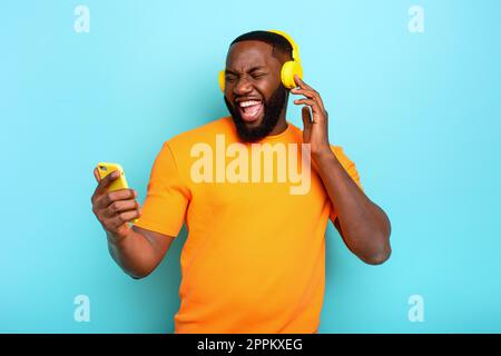 Ragazzo con auricolare giallo ascolta musica e danze. emozionale e espressione energica Foto Stock