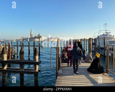 Persone che aspettano il vaporetto sul molo della città di Venezia Foto Stock