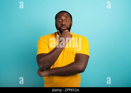 Confondere e pensieroso espressione di un ragazzo con molte domande . ciano sfondo colorato Foto Stock