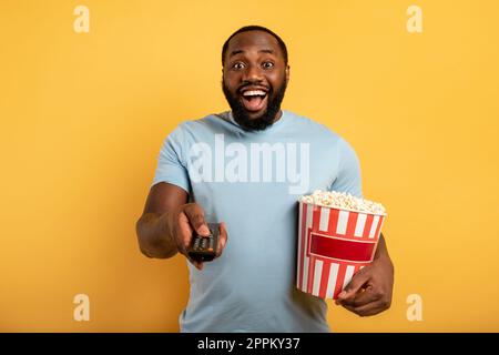 Ragazzo si diverte a guardare un film. Concetto di intrattenimento e TV in streaming. Sfondo rosso Foto Stock